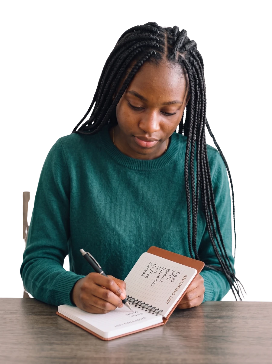 A woman writing in a notebook while planning a shopping list